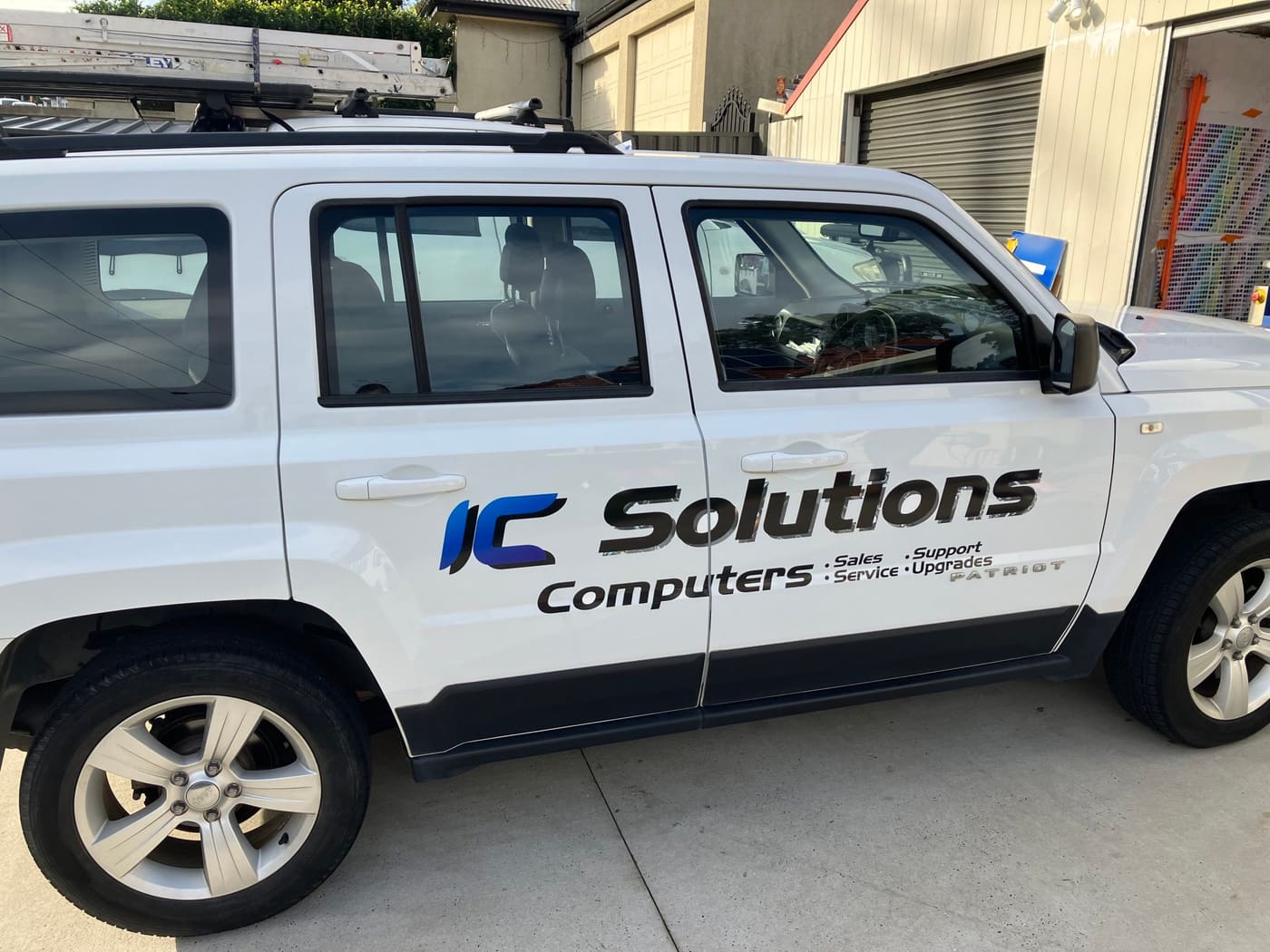 The white IC-Solutions Jeep Patriot with sign-written logo outside the Mayfield workshop